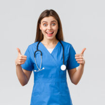 Medical workers, healthcare, covid-19 and vaccination concept. Enthusiastic and upbeat female nurse, doctor in blue scrubs, think wonderful idea, show thumbs-up in approval.